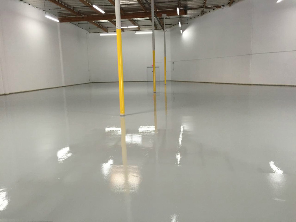 Light-gray solid epoxy floor in a commercial warehouse bay